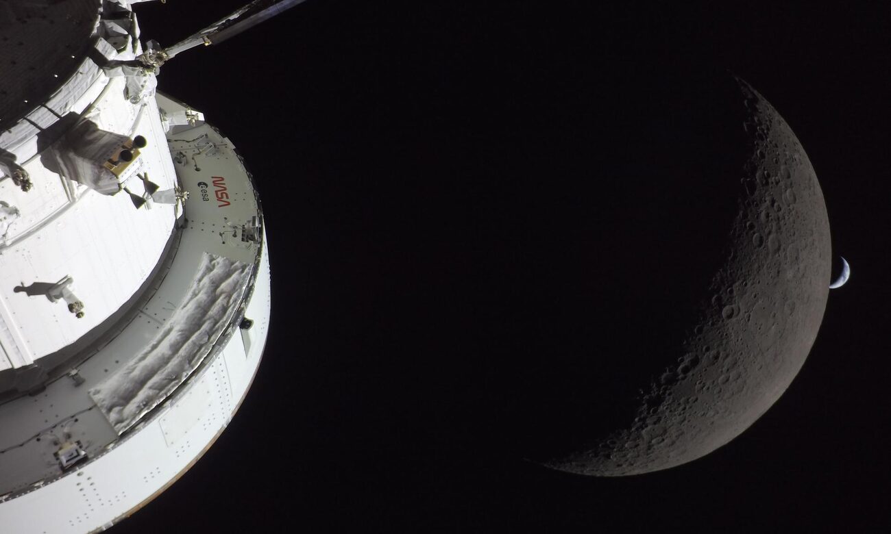 NASA's Orion spacecraft with the Moon and a crescent Earth behind it, photographed during Artemis II in April 2026